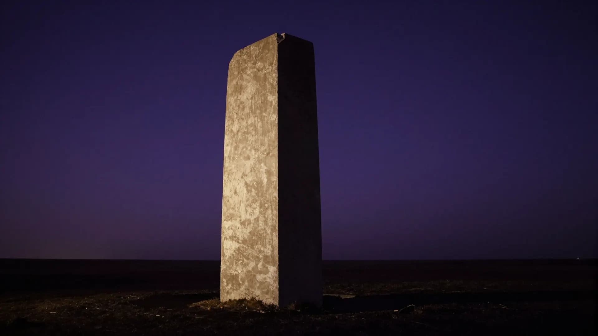 A concrete monolith half revealed by raking moonlight
